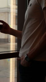 Midsection of woman standing by window