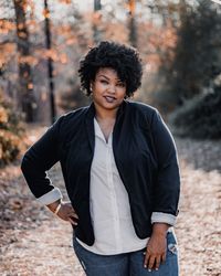 Portrait of smiling young woman standing against trees