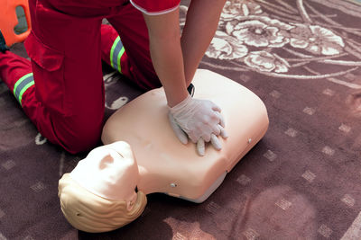 Midsection of paramedic performing cpr on dummy