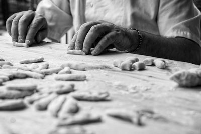 Midsection of man rolling dough on wooden table