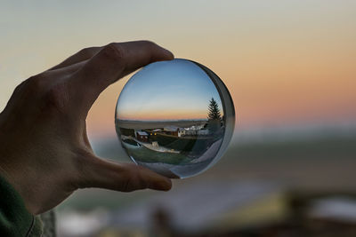 Close-up of hand holding glass against sky during sunset