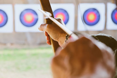 Cropped hands of woman with bow and arrow aiming at target