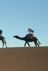 Low angle view of people on desert against clear sky