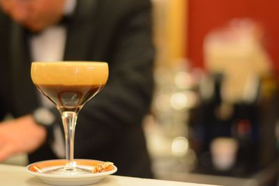 Close-up of coffee glass on table with man in background