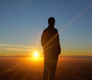 Rear view of silhouette man standing against sky during sunset