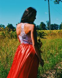 Rear view of woman standing on field against clear sky