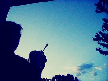 Low angle view of silhouette people against blue sky