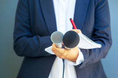 Female journalist at news conference or media event, writing notes, holding microphone