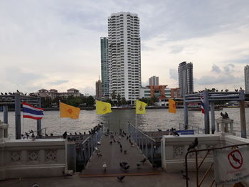 Modern buildings by river against sky in city