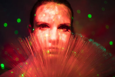 Close-up portrait of young woman against illuminated background