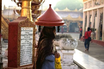 Woman carrying object on head while standing outside temple