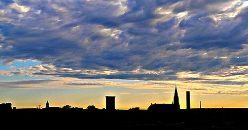 Buildings against cloudy sky at sunset