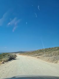 Road against clear blue sky seen through car windshield