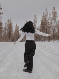 Rear view of young woman standing on snow covered land