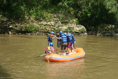 People in boat on river against trees