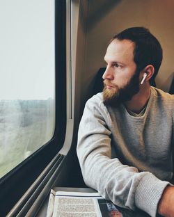 Portrait of young man looking through window