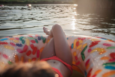 Girl relaxes on big donut inflatable ring on lake on hot summer day, happy summertime, countryside