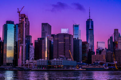 Modern buildings by river against sky in city