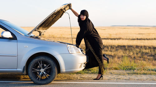 Islamic woman sitting in the car with the front door wide open.