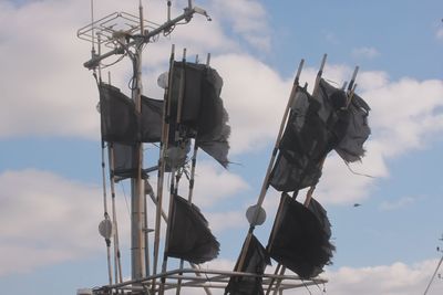 Low angle view of torn flags against sky
