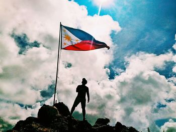 Low angle view of man flag on mountain against sky