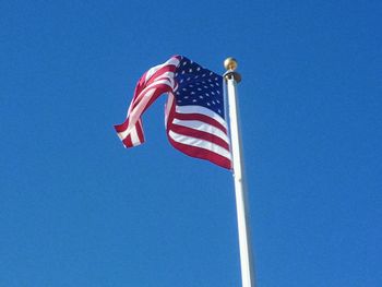 Low angle view of american flag against blue sky