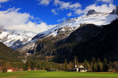 Church on field against snowy mountains