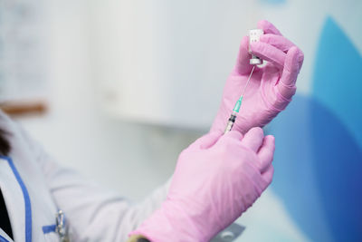 Midsection of person filling vaccine in syringe