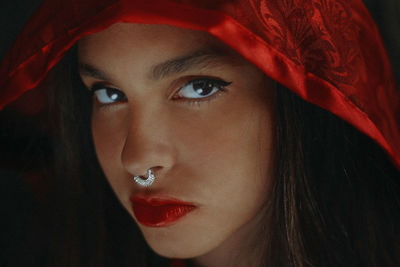 Close-up portrait of confident teenage girl wearing nose ring and hood