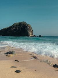 Scenic view of rocks on beach against clear sky