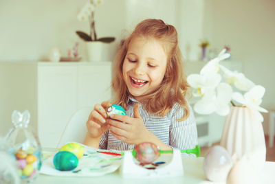 Cute girl holding easter egg while sitting at home