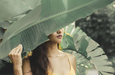 Portrait of young woman standing amidst plants