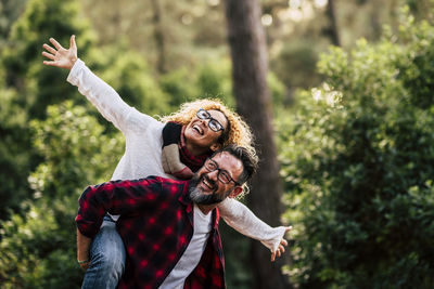 Smiling mature couple standing against trees