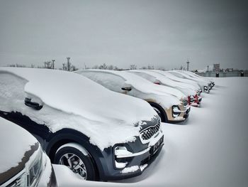 Vehicles on snow covered road against sky