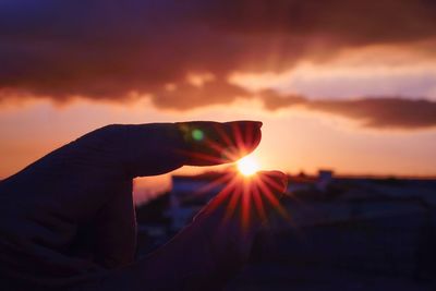 Person holding sun during sunset