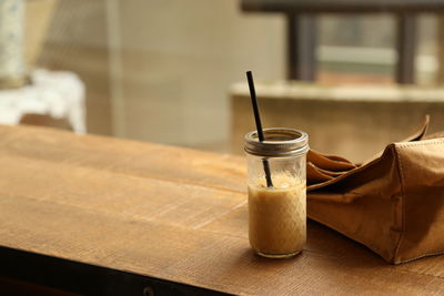 Close-up of drink by purse on table