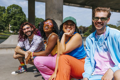 Portrait of happy male and female fashionable multiracial group of friends posing near overpass at sunny day