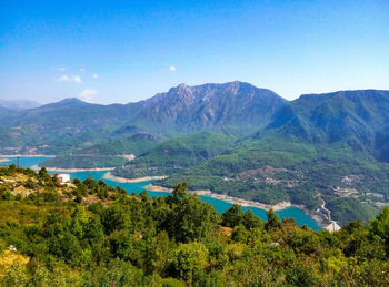 Scenic view of lake and mountains against blue sky