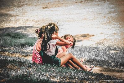 Rear view of mother and girl lying on land