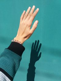 Close-up of human hand against turquoise wall