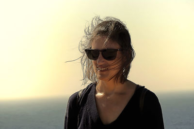 Portrait of young woman wearing sunglasses against sky during sunset