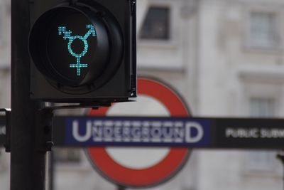 Close-up of green traffic light by sign board