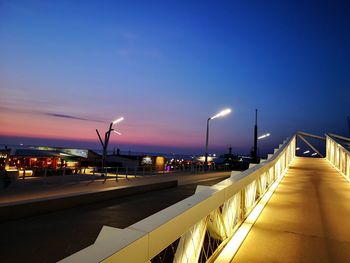 Illuminated street lights against sky at night