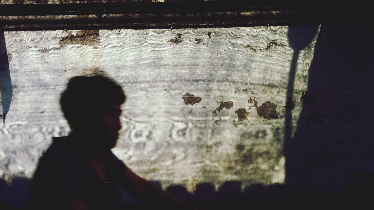 REAR VIEW OF SILHOUETTE MAN LOOKING THROUGH WALL