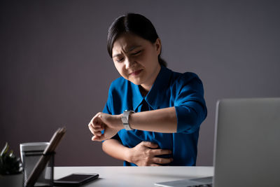 Mid adult woman using mobile phone while sitting on table