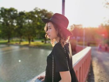 Beautiful young woman standing by lake in park