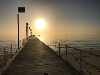 Pier over sea against sky during sunset