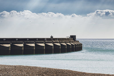 Sun rays break through over the ocean and the marina wall