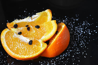 Close-up of orange fruit sprinkled with sugar and raisins