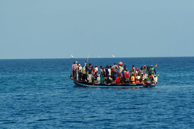 People on boat in sea against clear sky